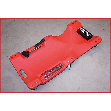 Rote Werkstattliege mit Werkzeug. Ein schwarzer Gummihammer, Schraubenschlüssel, Zangen und Schraubenschlüssel liegen auf der Liege.